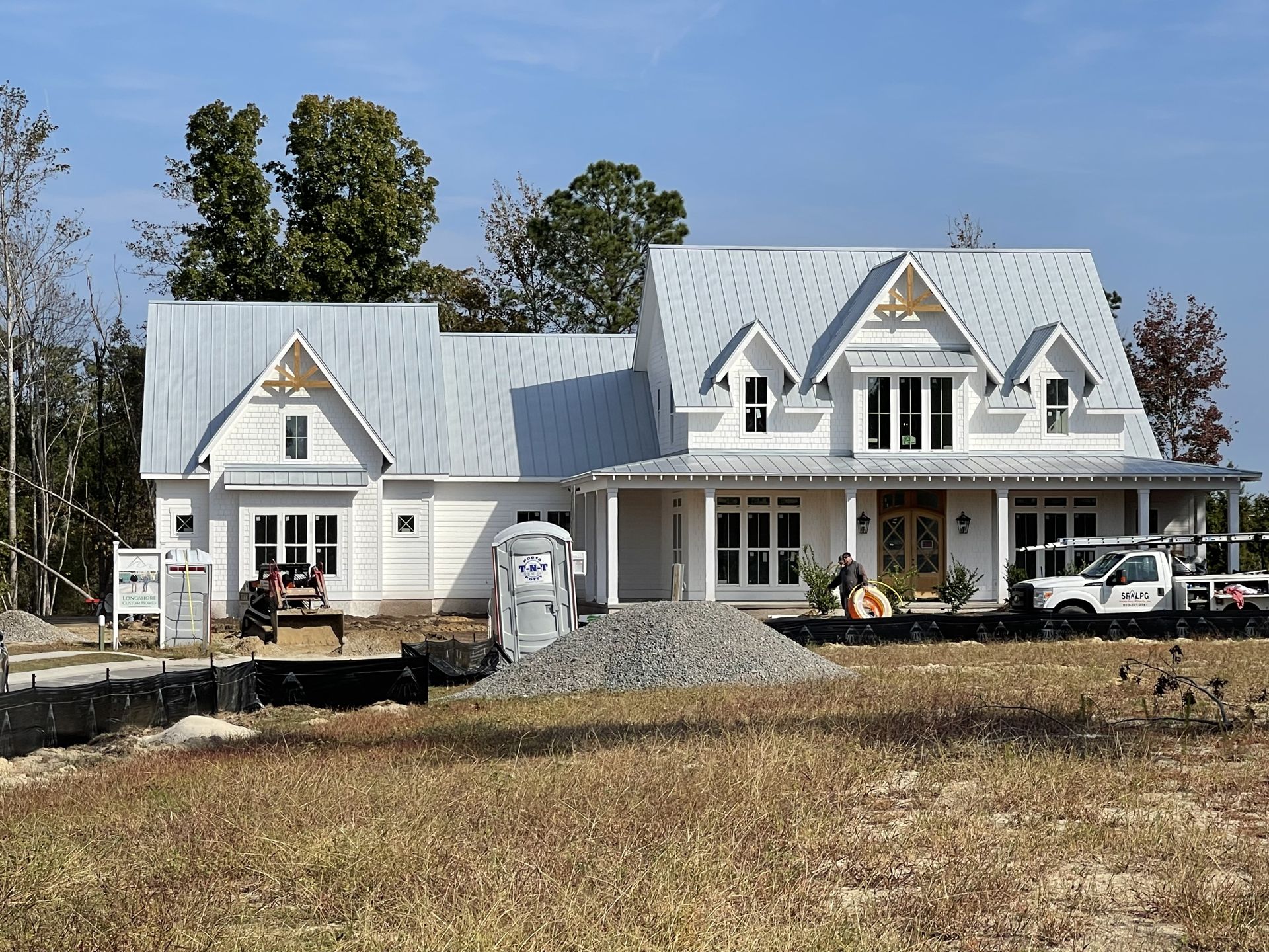 Newly completed white farmhouse with standing seam metal roof